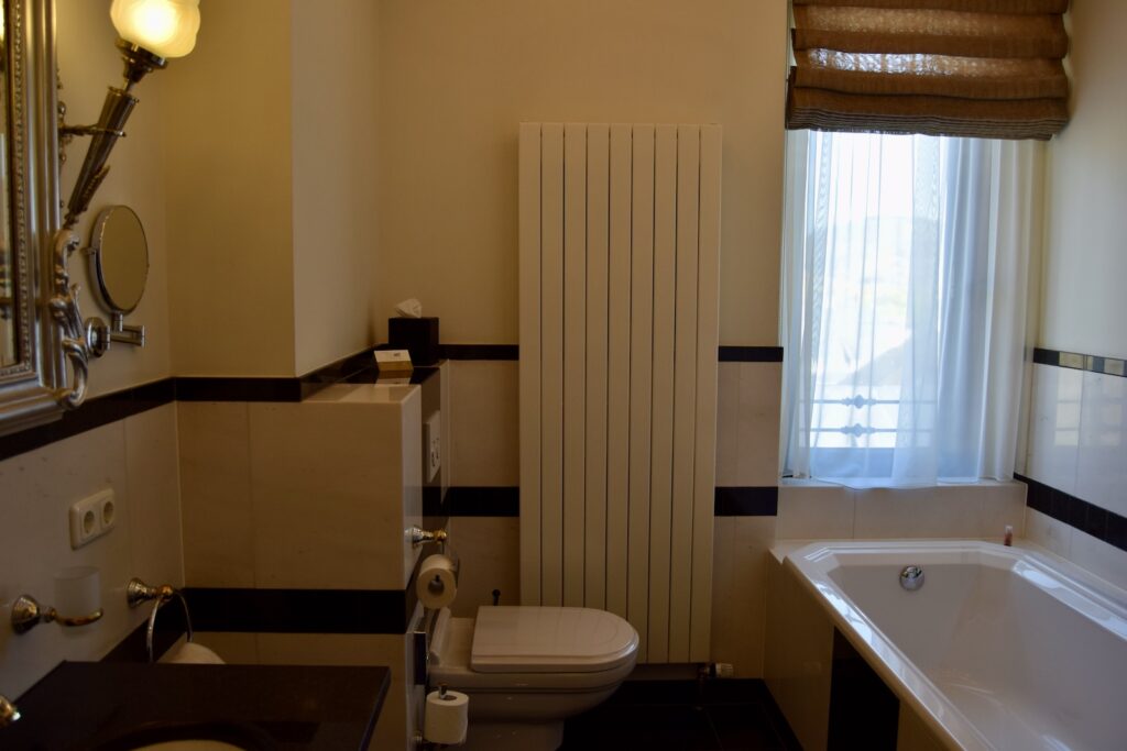 Im Haus, Wand, Installationszubehör, Hahn, Badezimmerzubehör, Wasserleitung, Spiegel, Inneneinrichtung, Badezimmer, Hotel, Zimmer, Kachel, Waschbecken, Badezimmerschrank, Arbeitsfläche, Vorhang, Fenster, Wanne, Toilette, Badewanne, Dusche
